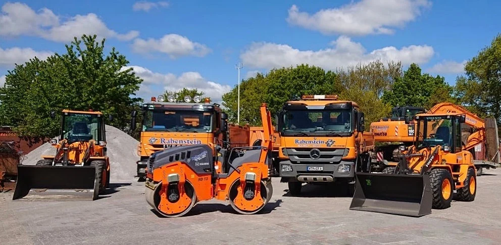 Der orangefarbene Fuhrpark von Rabenstein mit Lkw, Walze, Radlader und Bagger