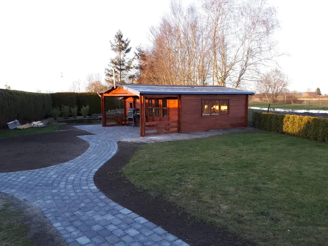 Geschwungener Pflasterweg an einem Gartenhaus.