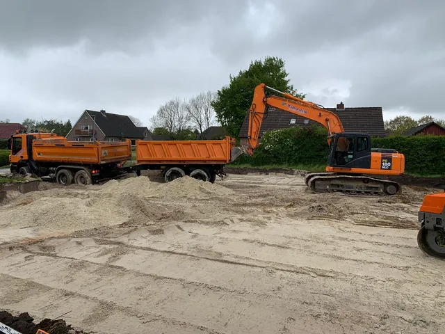 Bagger und Kipper bei der Arbeit auf einer Baustelle.